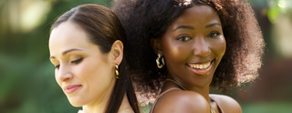 Two women standing close together with a blurred natural background
