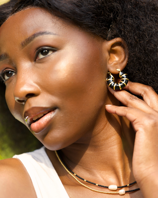 Woman wearing gold hoop earrings and necklaces outdoors