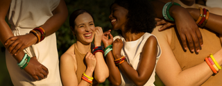 smiling and wearing colourful bracelets, with a blurred background.
