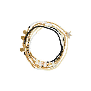 Multi-layer beaded bracelet stack featuring black, white, cream, and gold beads with natural shell accents, polished gold discs, and a sparkling starfish charm for a coastal-inspired layered look.