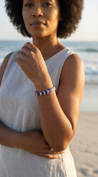 A woman wearing the Chevron-inspired Purple Reign Bracelet, adding bold geometric detail to a relaxed coastal outfit.