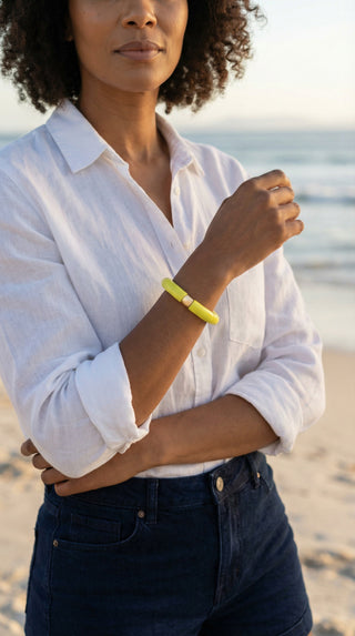 Model wearing the Morning Marabi lime green resin bracelet with a gold accent bead, styled with a white linen shirt.
