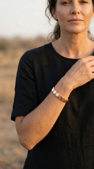 A woman wearing the Queens Honeycomb Gold Bracelet, showcasing its geometric gold links against effortless everyday styling.