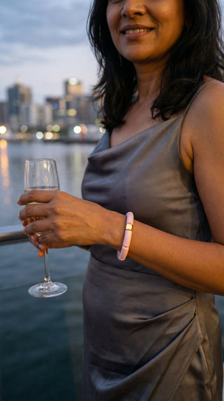 A guest enjoying an evening by the water, wearing a blush pink resin bracelet that adds a delicate touch of colour to a sophisticated outfit.
