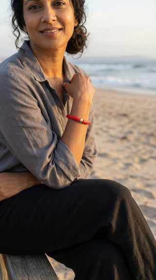 A lady wearing a vibrant red resin bracelet at the beach, adding a confident pop of colour to a relaxed coastal outfit.