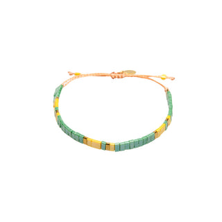 Delicate green and gold beaded bracelet featuring fine tile beads, polished gold accents, and an adjustable cord closure for a lightweight, contemporary finish.
