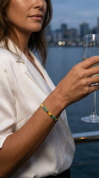 A fashionable lady wearing a green and gold beaded bracelet, adding a subtle pop of colour and refined detail to an elegant evening ensemble.
