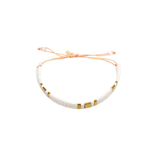 Elegant white and gold beaded bracelet featuring fine tile beads, polished gold accents, and an adjustable cord closure for a clean, minimalist finish.