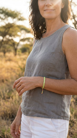 A woman wearing a light green adjustable tile beaded bracelet, adding a fresh and understated touch to a relaxed linen outfit with effortless everyday elegance.
