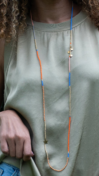 A woman wearing a colourful layered beaded necklace with blue, coral, pink, and gold accents, creating a relaxed yet elegant look that adds a vibrant touch to everyday style.