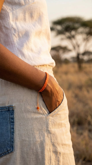 A woman wearing a vibrant orange adjustable tile beaded bracelet, adding a bold yet effortless accent to a relaxed everyday outfit with modern casual style.
