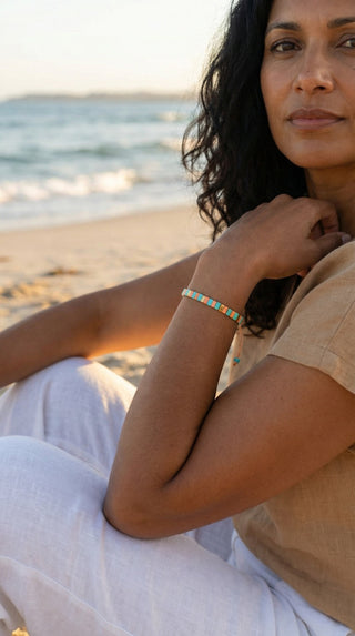 A woman wearing a colourful turquoise and coral tile beaded bracelet, adding a fresh, playful accent to a relaxed beach-inspired outfit with effortless everyday style.