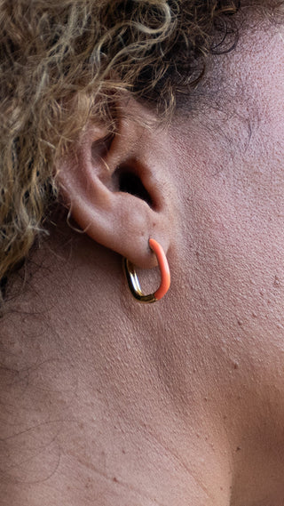 A lady wearing coral hoop earrings that add warmth and contemporary charm to an effortlessly polished look.