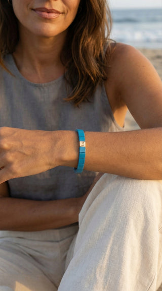 A lady styling a turquoise bracelet that complements a light summer outfit.